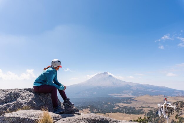 Caminante femenino que mira el volcán humeante