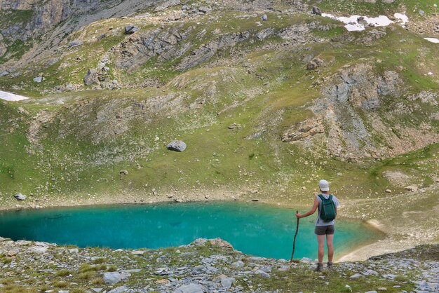 Caminante en frente del pequeño lago alpino