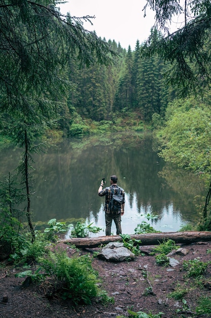 Caminante fuerte del hombre que mira el lago de la montaña