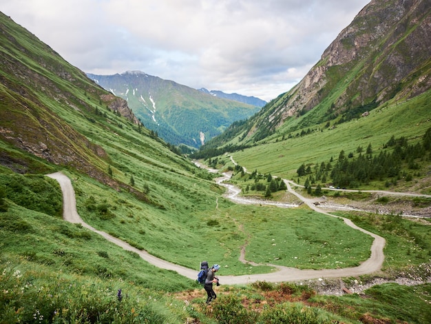 Caminante masculino que camina abajo del prado de la ladera en Austria