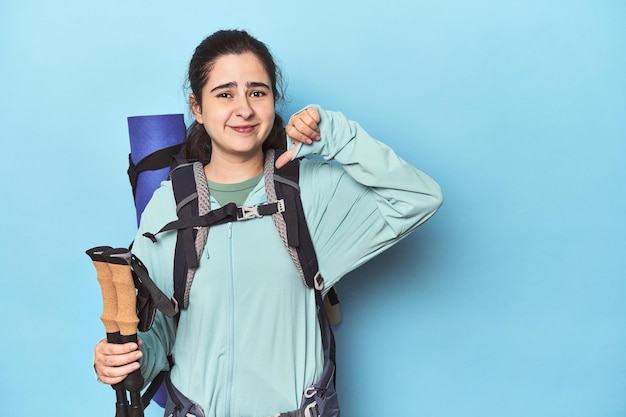 Caminante con mochila y bastones en azul mostrando un gesto de disgusto con el pulgar hacia abajo Concepto de desacuerdo