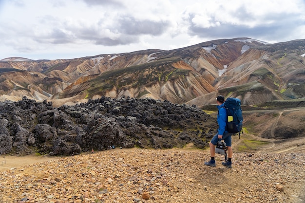 Caminante con mochila mirando Landmannalaugar Valley. Islandia. Montañas coloridas en la ruta de senderismo de Laugavegur. La combinación de capas de rocas multicolores, minerales, hierba y musgo.