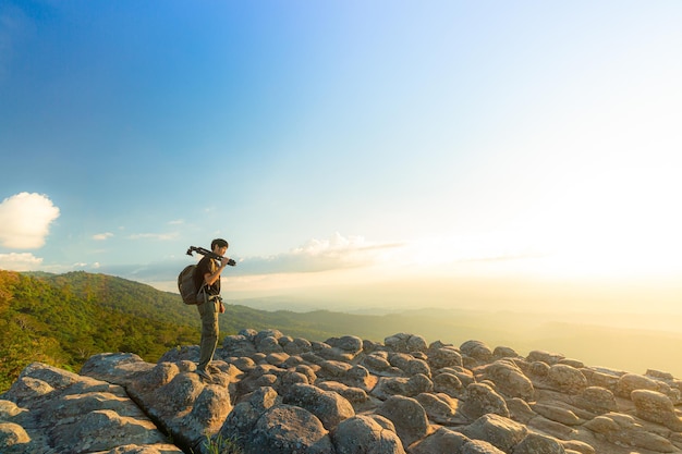 Caminante con una mochila de pie en la cima de una montaña por encima de las nubes