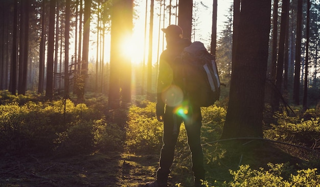 Caminante con mochila se relaja en el bosque y disfruta de la vista de la puesta de sol