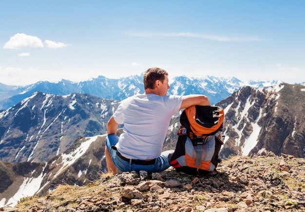 Caminante con mochila sentado en la cima de una montaña, viajando montañas y costa, libertad y concepto de estilo de vida activo.