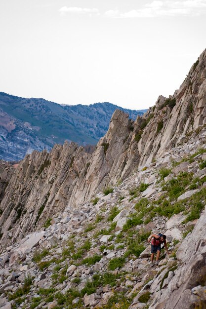 Caminante en una montaña rocosa contra el cielo