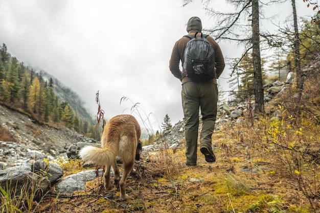 Caminante va a las montañas con un perro rojo en el bosque de otoño Libertad y caminatas activas para una mascota