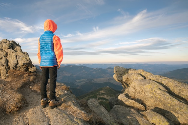 Caminante del muchacho del niño joven que se coloca en las montañas que disfruta de la visión.