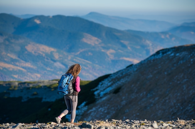 El caminante de la mujer está bajando de la montaña plato