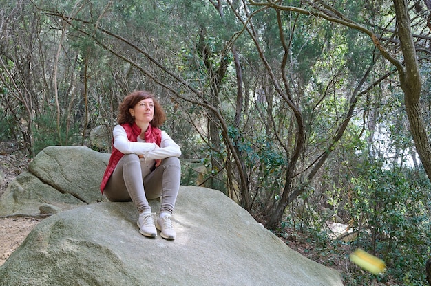 Caminante mujer sentada sobre una piedra en la montaña
