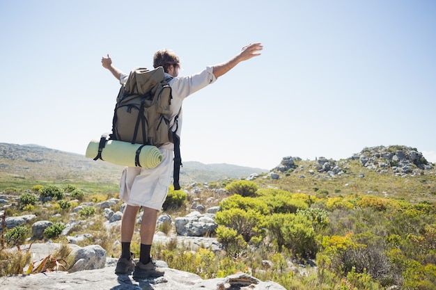 Caminante de pie en la cumbre con los brazos extendidos