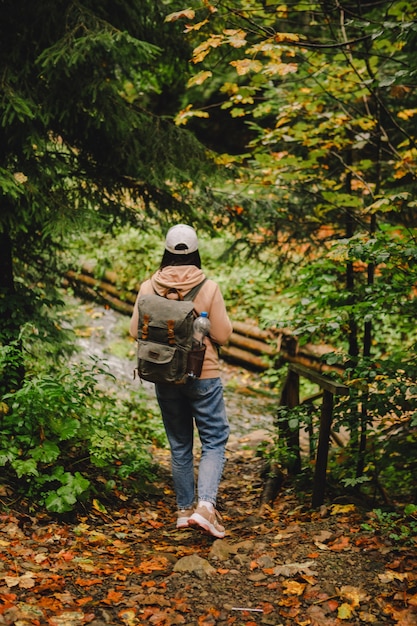 Foto caminante sonriente mujer caminando por el espacio de copia de camino forestal de otoño