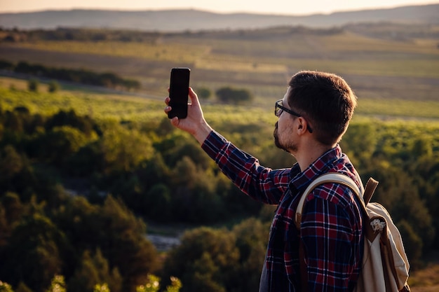 Caminante tomando fotos del hermoso paisaje montañoso con teléfono móvil