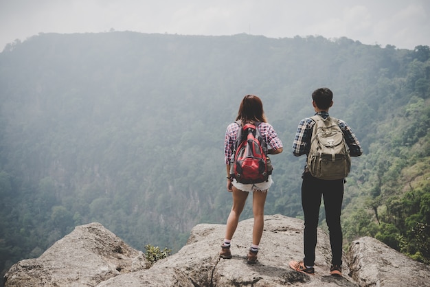 Caminantes pareja con mochilas de pie en la cima de una montaña y disfrutar de la naturaleza ver