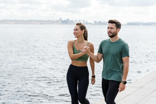 Caminata casual a la orilla del río con una pareja satisfecha que subraya un compromiso compartido con un estilo de vida en forma