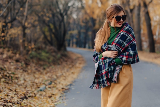 Caminata elegante y acogedora de la chica joven en el parque colorido del otoño