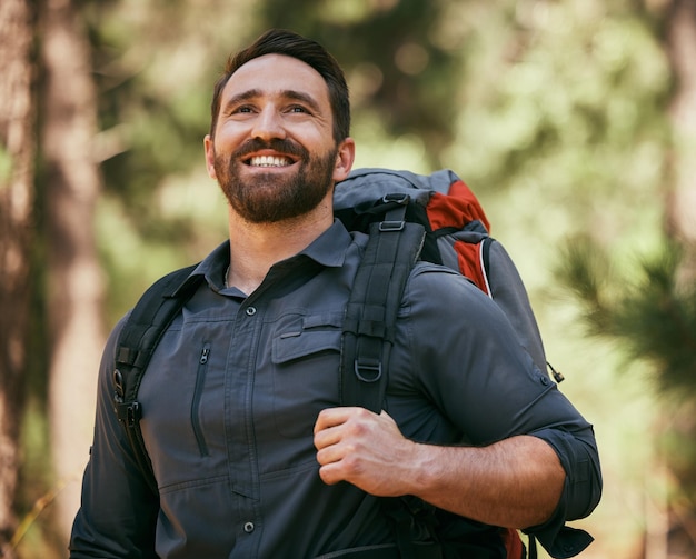 Caminata con mochila y hombre en la naturaleza con gratitud de senderismo fitness y aventura en la selva tropical Feliz sonrisa y viaje con bolsa y viaje en vacaciones ecológicas al aire libre con viaje y pensamiento