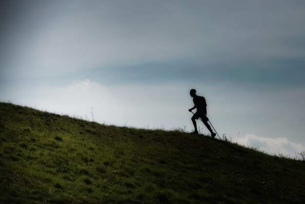 Caminata nórdica cuesta arriba en una pradera montañosa en silueta