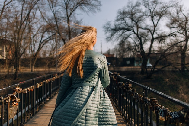 Caminata de otoño frío de niña con propósito. Mujer, con, viento, en, pelo, vista trasera