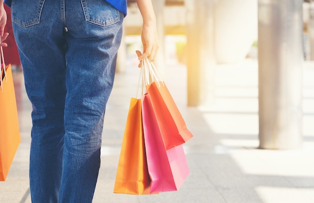 Caminhada da jovem mulher na maneira do trajeto com saco de compras colorido.