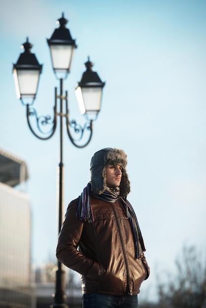 Caminhada de inverno jovem com um chapéu de orelha em pé sob o poste de luz
