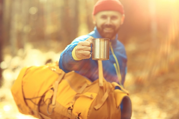 caminhada de outono com uma mochila, raios de sol, paisagem de outono, um homem no brilho da floresta do pôr do sol