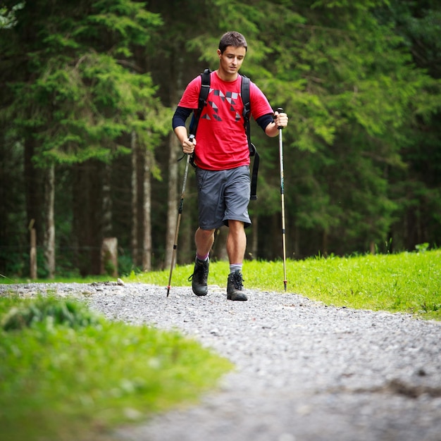 Caminhada nórdica de um jovem bonito e ativo caminhando nas montanhas aproveitando o ar livre