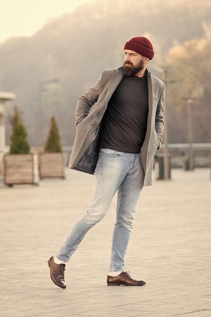 Caminhada refrescante Roupa hipster e acessório de chapéu Roupa casual elegante temporada de primavera Moda masculina e conceito de moda masculina Homem barbudo hipster elegante casaco e chapéu elegante Roupa confortável