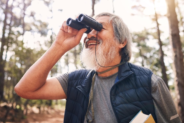 Caminhadas de binóculos e homem sênior na natureza olhando para ver passeios ou assistindo busca de aventura binocular e homem idoso feliz com binóculos trekking ou explorando em férias ao ar livre