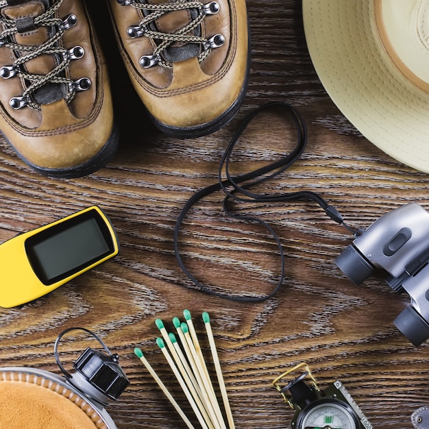 Caminhadas ou viagens equipamentos com botas, bússola, binóculos, fósforos em fundo de madeira. Conceito de estilo de vida ativo