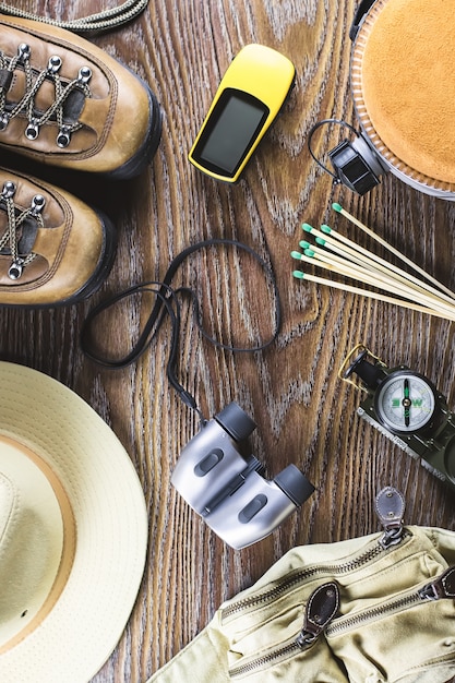 Caminhadas ou viagens equipamentos com botas, bússola, binóculos, fósforos em fundo de madeira. Conceito de estilo de vida ativo