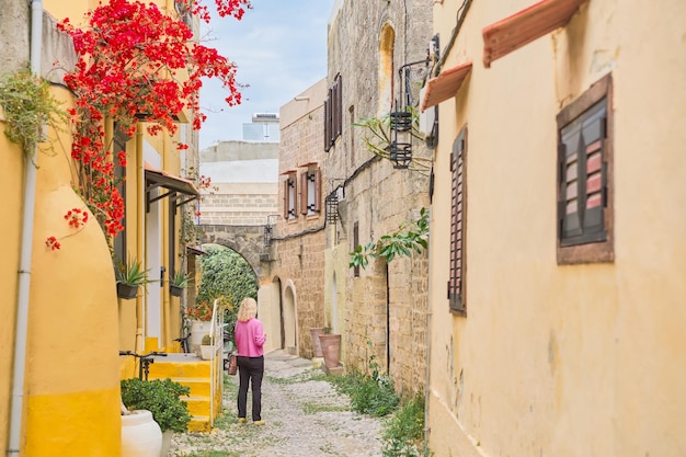 Caminhando pelas ruas da cidade velha de Rodes, longe dos locais turísticos, uma mulher adulta caminha pela rua em uma viagem aos locais populares do arquipélago do Dodecaneso, Grécia