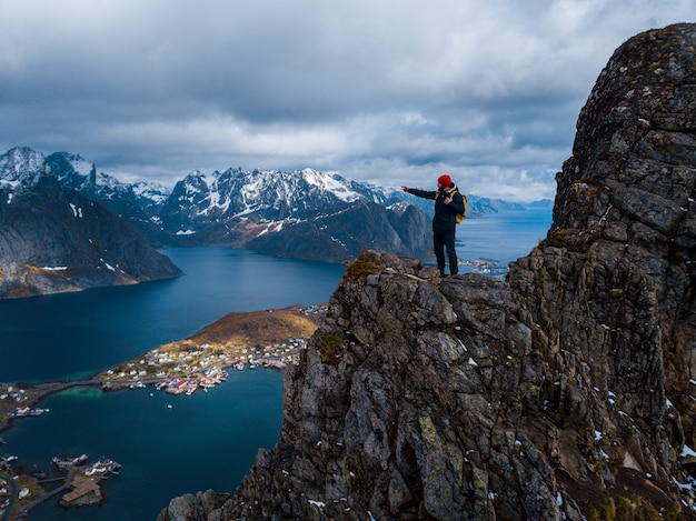 Caminhante com mochila apreciando a paisagem do pôr do sol em Lofoten, Noruega