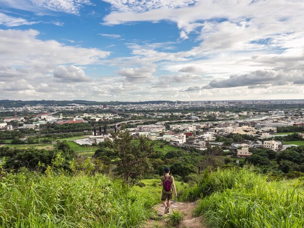 caminhante e vista da cidade da bela montanha. Céu azul e prado verde