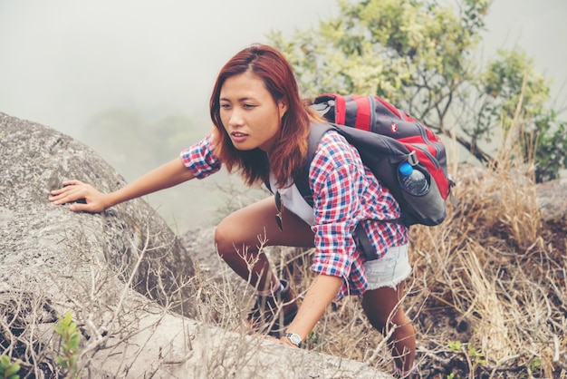 Caminhante jovem asiático que escalada no penhasco de montanha.