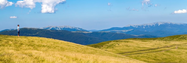 Caminhante solitário em uma ampla colina apreciando a vista da montanha