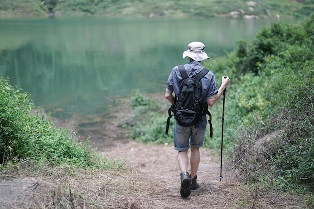 Caminhantes caminhando por uma trilha em uma montanha com bastões de caminhada Turismo de aventura caminhada e conceito de pessoas Grupo de amigos sorridentes com mochilas ao ar livre