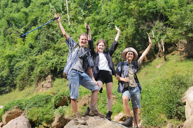 Foto caminhantes caminhando por uma trilha em uma montanha com bastões de caminhada turismo de aventura caminhada e conceito de pessoas grupo de amigos sorridentes com mochilas ao ar livre