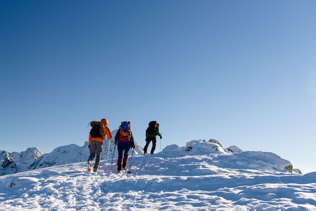 Caminhantes em grupo nas montanhas de inverno bela paisagem e céu azul