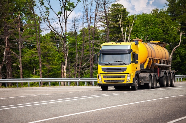 Foto caminhão amarelo com semirreboque tanque laranja em uma estrada