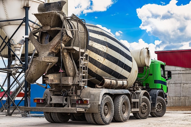 Foto caminhão betoneira na frente de uma fábrica de cimento de planta dosadora de concreto carregando caminhão betoneira closeup entrega de concreto para o canteiro de obras trabalhos monolíticos de concreto