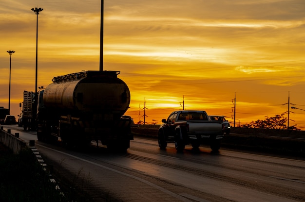 Foto caminhão com carga dirigindo na rodovia de transporte rodoviário ao pôr do sol no verão