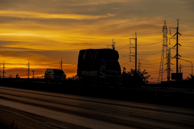 Caminhão com carga dirigindo na rodovia de transporte rodoviário ao pôr do sol no verão