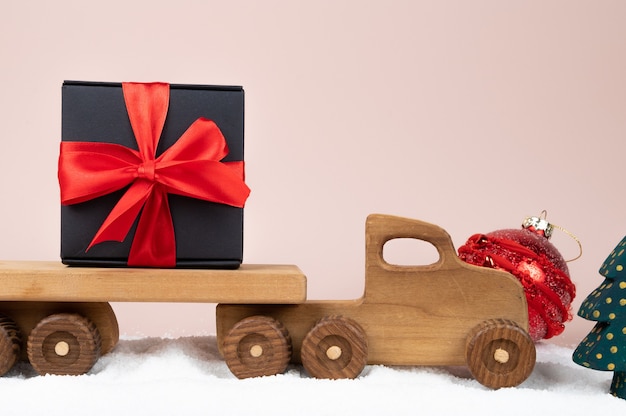 Caminhão de brinquedo de madeira com caixa de presente de Natal em fundo rosa. Cartão de férias. Foto de alta qualidade