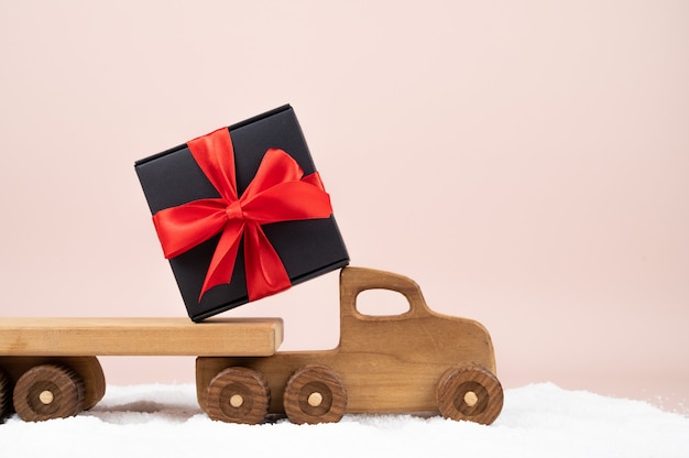 Caminhão de brinquedo de madeira com caixa de presente de Natal em fundo rosa. Cartão de férias. Foto de alta qualidade