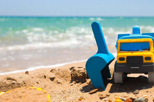 Caminhão de brinquedo e pás para brincar na areia da praia