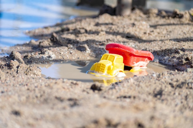 Caminhão de brinquedo infantil em poça de lama na areia molhada