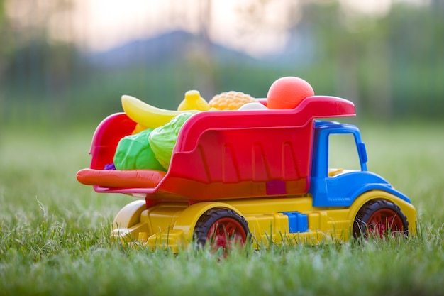 Caminhão de carro de brinquedo de plástico colorido brilhante carregando cesta com frutas e legumes de brinquedo
