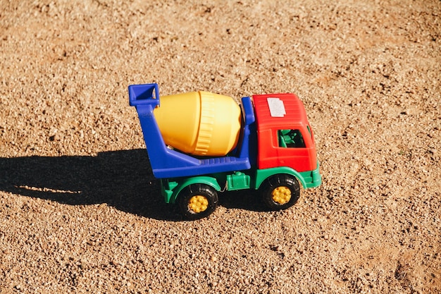 Foto caminhão multicolorido de brinquedo plástico na areia