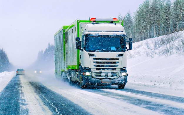 Caminhão na estrada de inverno de neve da Finlândia. Caminhoneiro na rodovia. Caminhão fazendo trabalho de logística. Semi reboque com motorista. Grande movimentação de carro de carga. Entrega de frete. Indústria de exportação de transporte. Recipiente com mercadorias